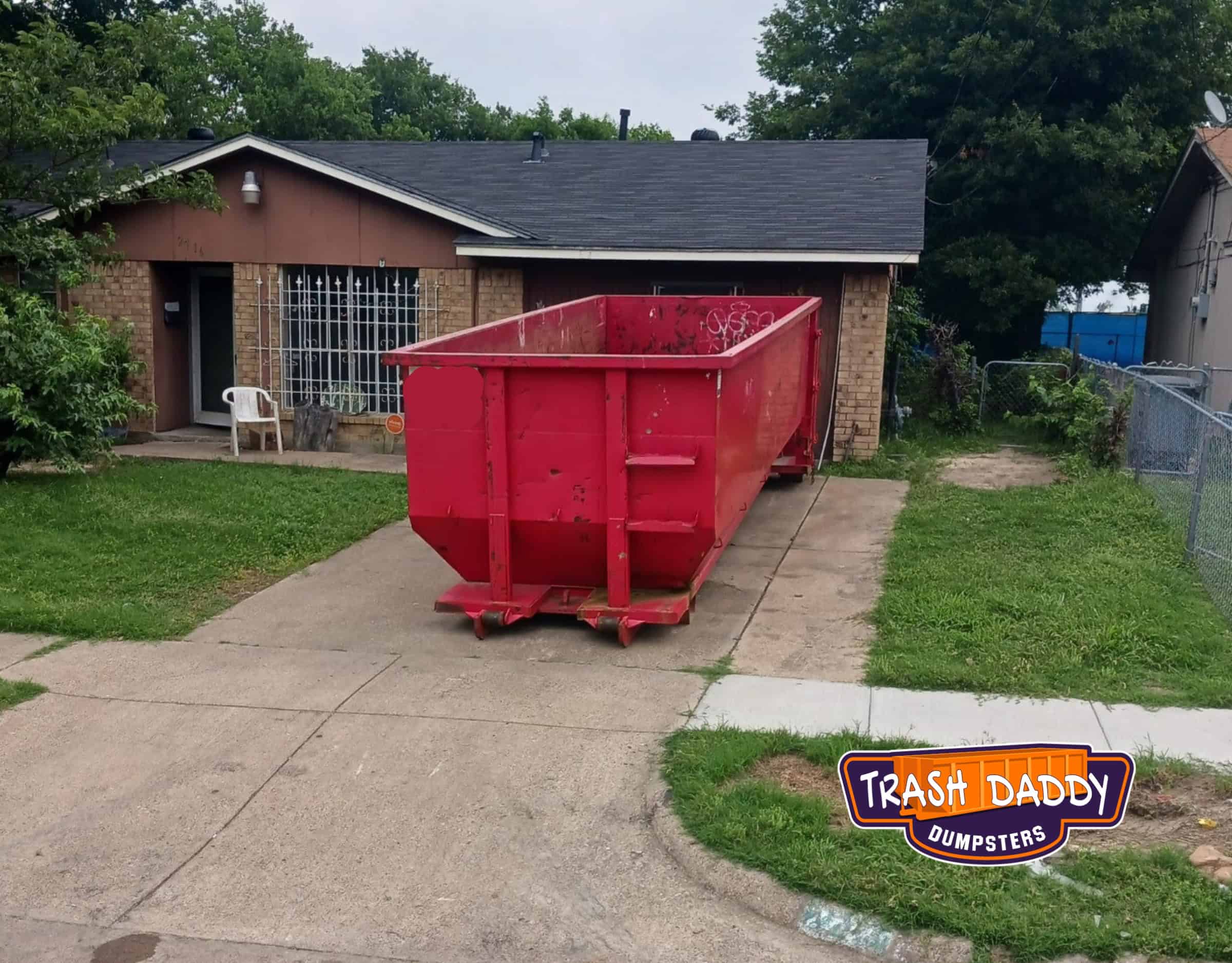 red 30 yard dumspter in a residential driveway